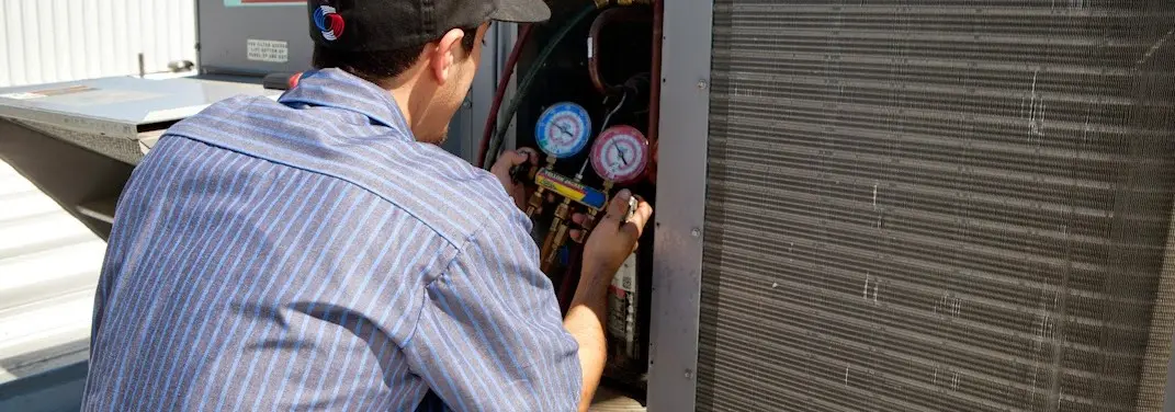 HVAC technician servicing a condenser unit in North Decatur